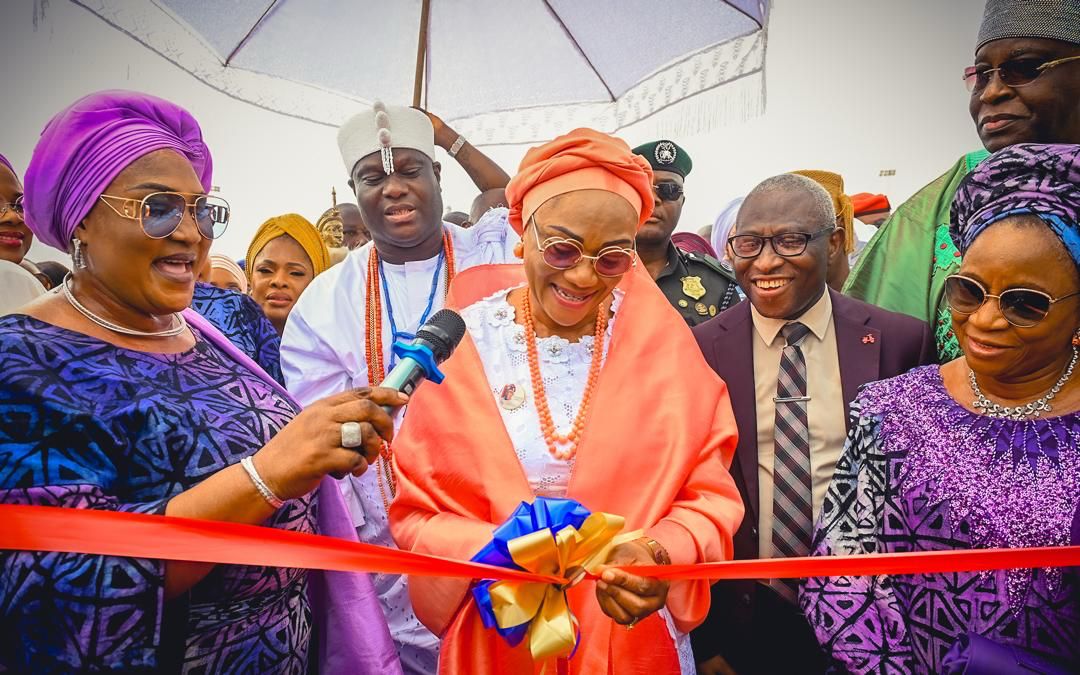 First Lady Senator Oluremi Tinubu, CON, cuts a ribbon during an outdoor commissioning ceremony, flanked by dignitaries including the Ooni of Ife.