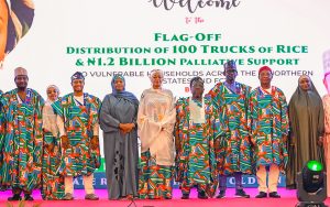 First Lady Senator Oluremi Tinubu, CON, and government officials standing on stage in front of a banner detailing the distribution of 100 trucks of rice and palliative support.