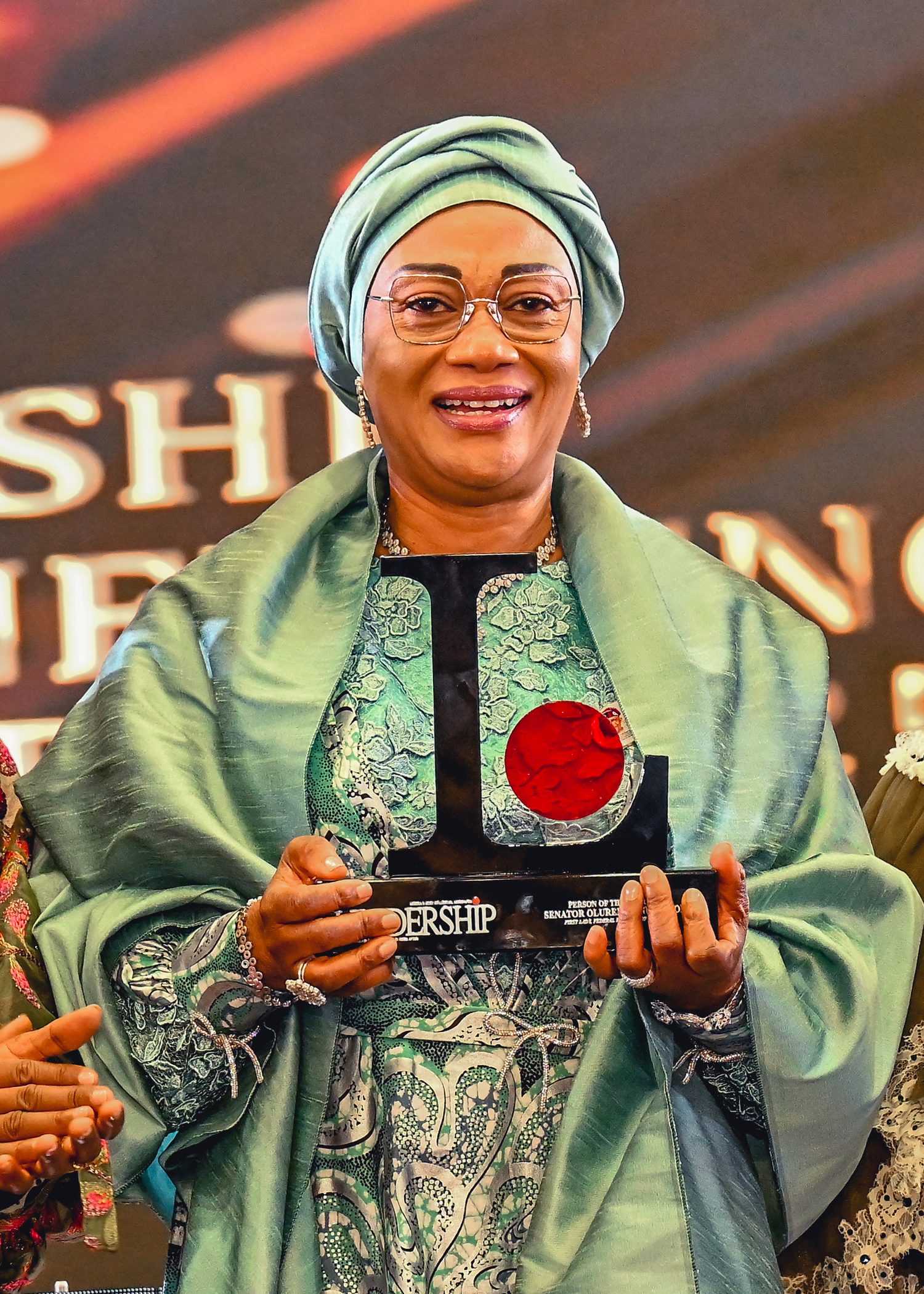 First Lady Senator Oluremi Tinubu, CON, smiling while holding a "Leadership" award plaque.