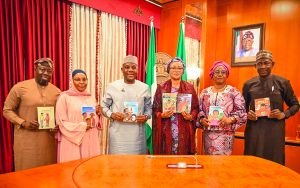 First Lady Senator Oluremi Tinubu, CON, standing center holding storybooks alongside a group of officials who are also holding books in an office setting.