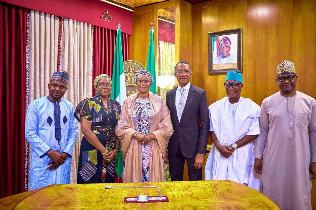 First Lady Senator Oluremi Tinubu, CON, poses for a group photograph with officials and delegates indoors.